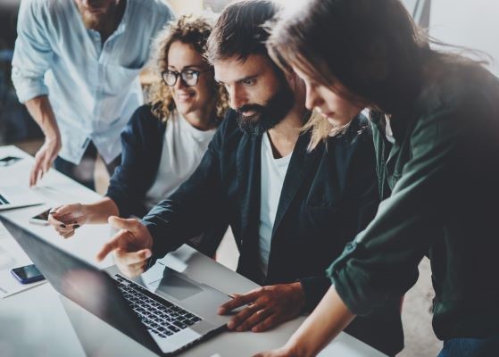 Four professionals looking at a laptop discussing a project